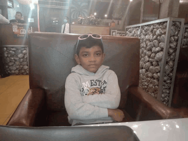 a young boy wearing sunglasses sits in a chair with his arms crossed in front of a free wifi zone