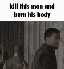 a man is standing in front of a wall with the words `` kill this man and burn his body '' on it .