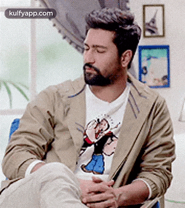 a man with a beard is sitting in a chair with his eyes closed and a cup of coffee in his hand .