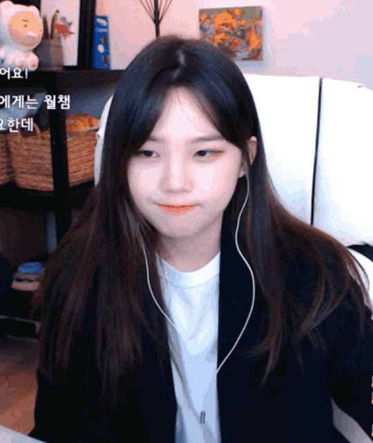 a girl wearing ear buds and a white shirt looks at the camera with a bear in the background