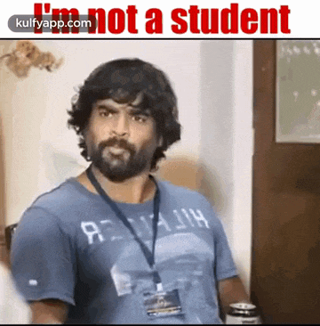a man with a beard is wearing a blue shirt that says i 'm not a student .