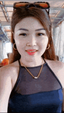 a woman wearing sunglasses and a necklace is taking a selfie with her phone .