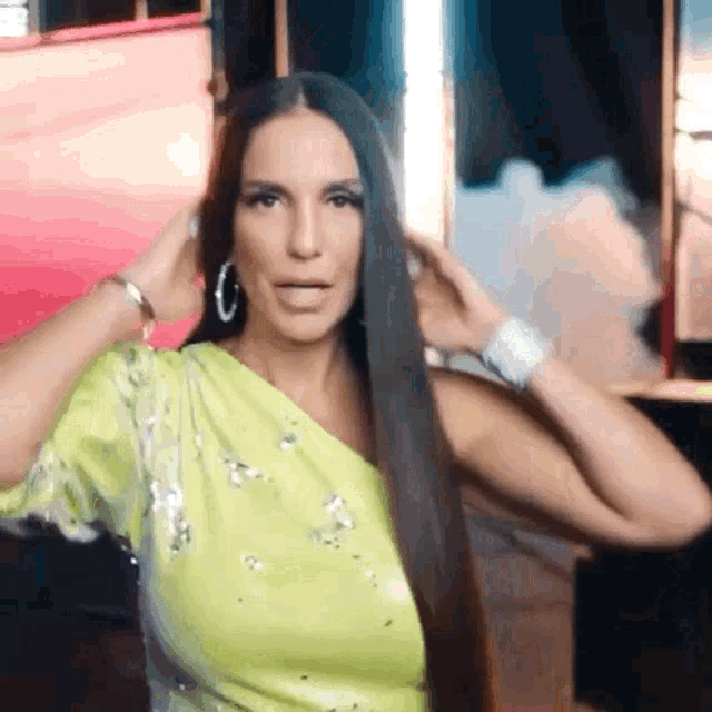 a woman with long black hair is wearing a neon yellow dress and hoop earrings .