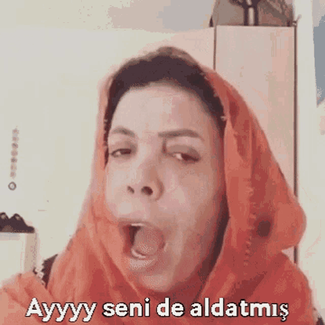 a woman wearing an orange head scarf is making a funny face