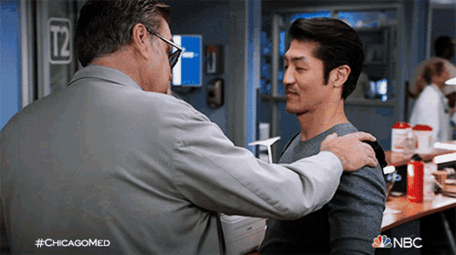 a man is hugging another man in front of a sign that says " t2 "