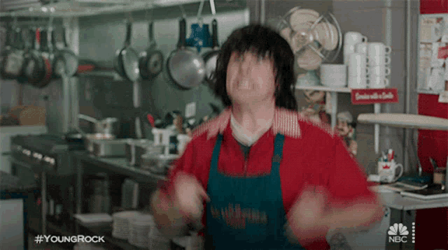 a man in an apron is dancing in a kitchen with #youngrock written on the bottom of the screen