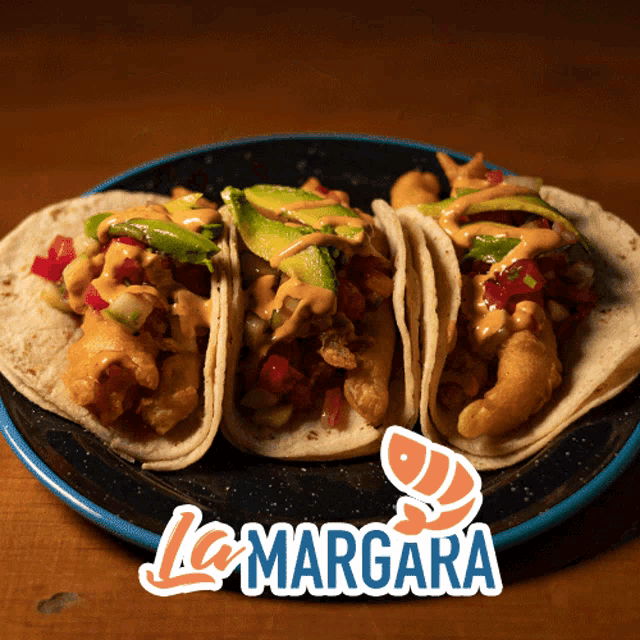 three tacos on a black plate with la margarita written on it