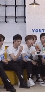 a group of young men are sitting on a couch eating .