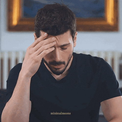 a man with his hand on his forehead has minimalmoons on the bottom right