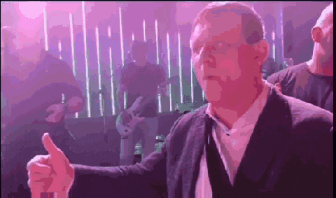 a man in a suit is giving a thumbs up in front of a purple background
