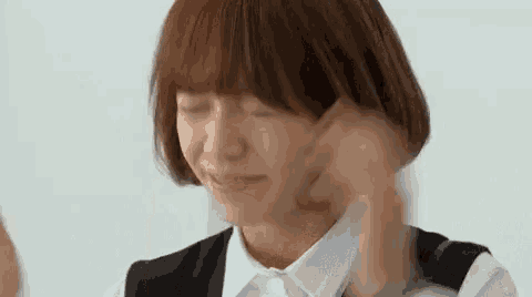 a woman with short hair is smiling and holding her hair .