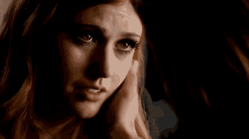 a close up of a woman 's face with a hand on her face .