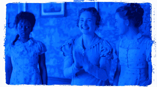 three women are standing next to each other in a room with a blue light behind them