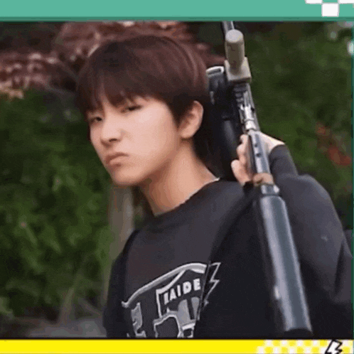 a young boy is holding a gun over his shoulder and looking at the camera .