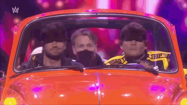 three men are sitting in a red car with the word trip on the side