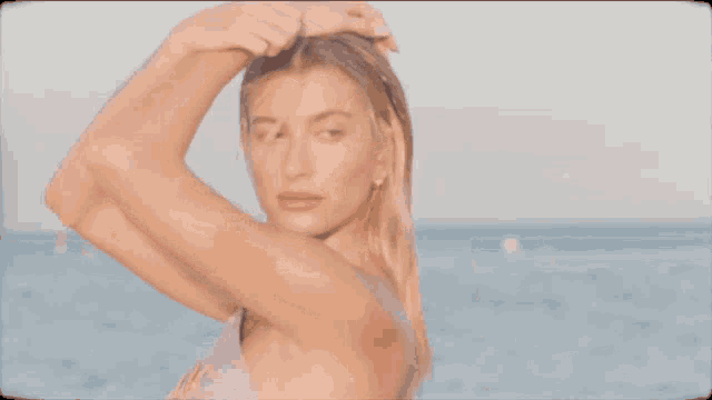 a woman in a bikini is standing in front of the ocean with the word elle on the bottom