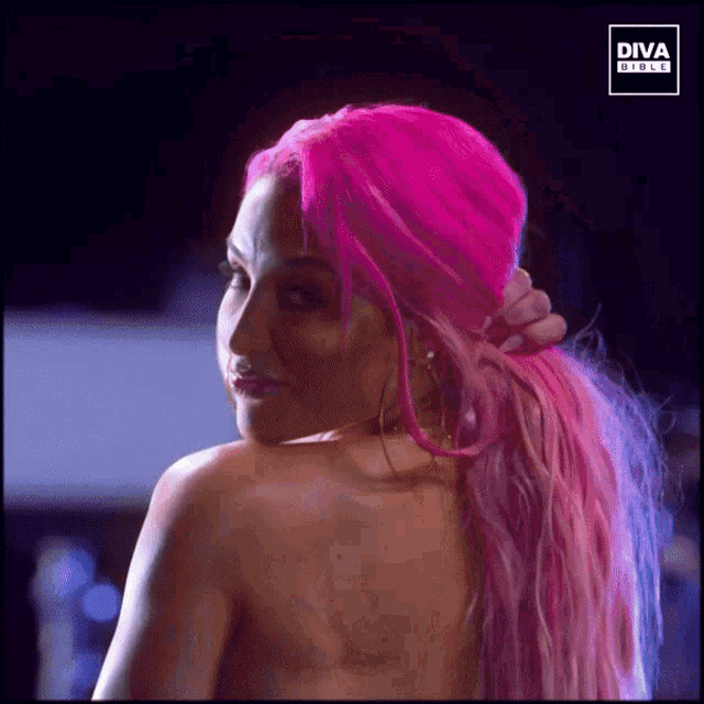 a woman with bright pink hair is standing in front of a diva girls sign