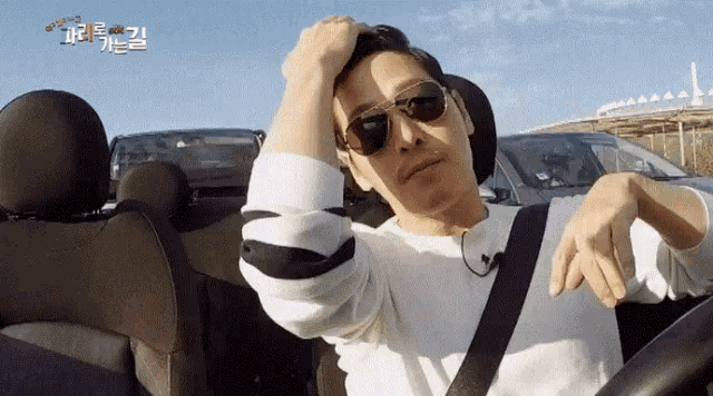 a man wearing sunglasses is sitting in the back seat of a convertible car