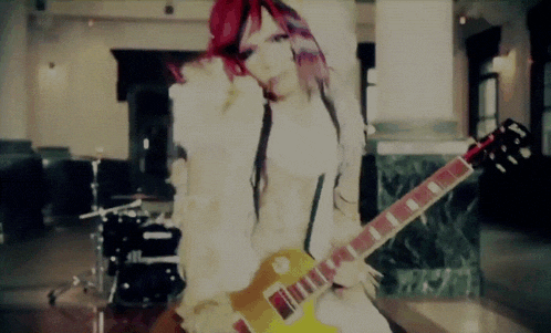 a girl with red hair is playing a yellow guitar