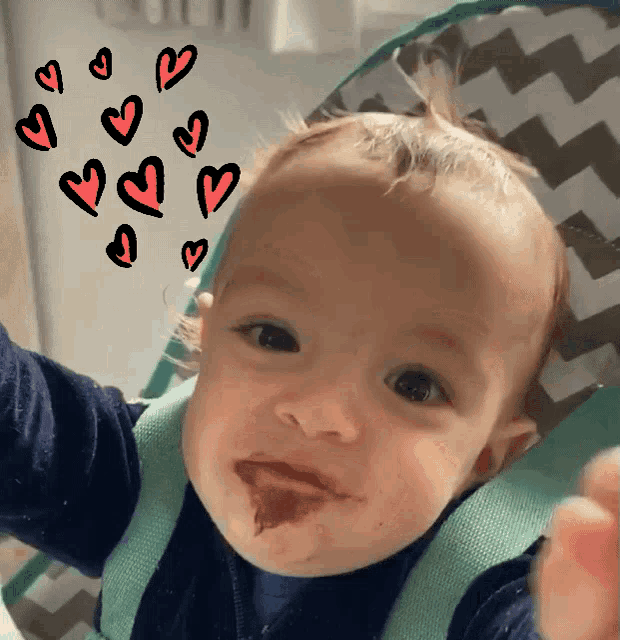 a baby is sitting in a high chair with hearts drawn on it