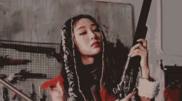 a woman with dreadlocks is holding a gun in her hands