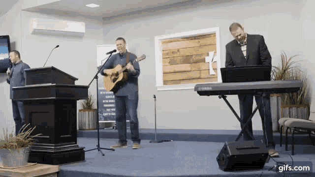 a man playing a guitar and another man playing a keyboard on stage
