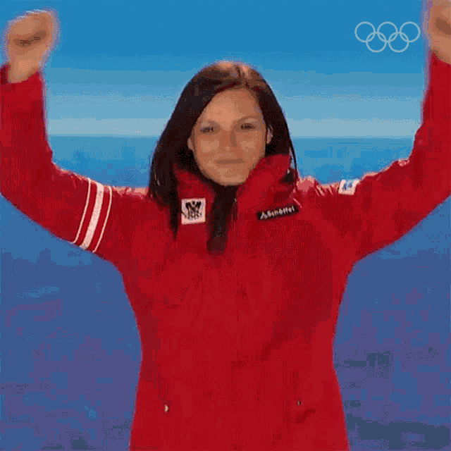 a woman wearing a red jacket with the olympic rings on her chest