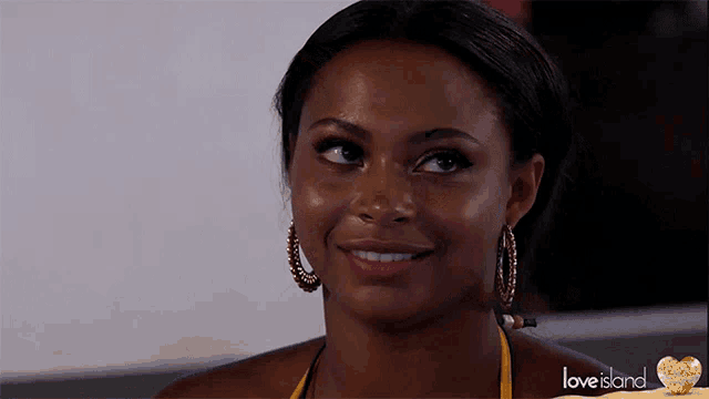 a close up of a woman wearing hoop earrings with the words love island on the bottom