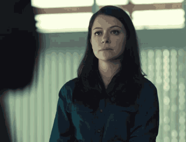 a woman in a blue shirt is looking at someone