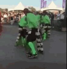a group of people in green and black costumes are dancing