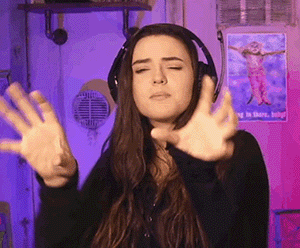 a woman wearing headphones is making a funny face while holding her hands up .