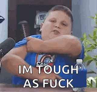 a fat boy is sitting at a table with a microphone and a bottle of water and making a funny face .
