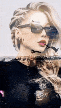 a woman wearing sunglasses is standing on a beach with seagulls flying in the background .