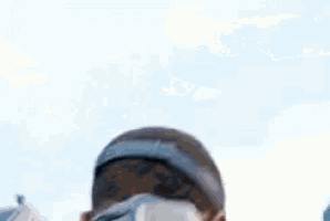 a close up of a person 's face with a blurred background and a blue sky in the background .