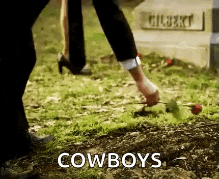 a man is putting a rose in the dirt at a grave .