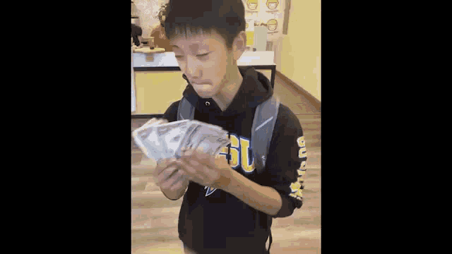 a young boy is holding a bunch of money in his hands and making a funny face .
