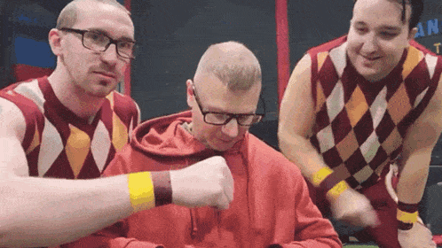 a man wearing glasses and a red sweater has a yellow wristband on his arm