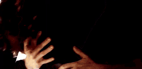 a man and a woman are kissing in a dark room with the sun shining through the window .
