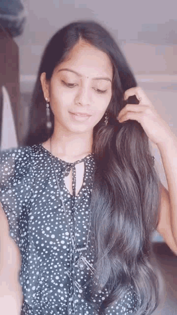 a woman with long hair is wearing a black and white polka dot shirt .