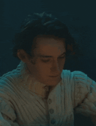 a close up of a man wearing a white sweater and tie with his eyes closed .