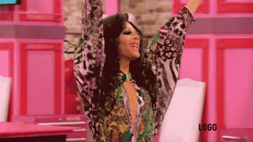 a woman in a floral shirt is standing with her arms in the air .