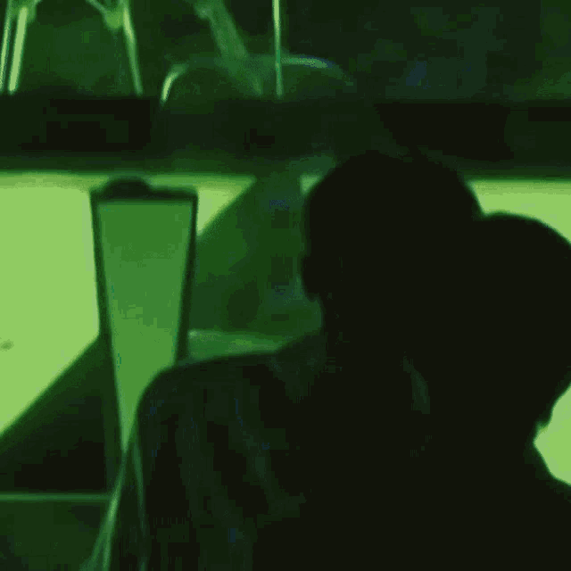 a person is sitting in a dark room with a green background
