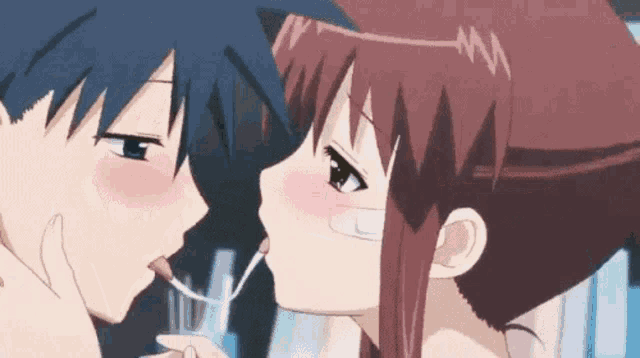 a boy and a girl are kissing with a spoon in their mouth .