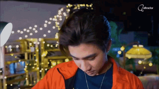 a man wearing an orange jacket and a blue shirt is looking down