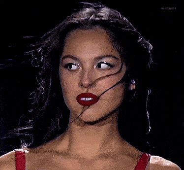 a close up of a woman 's face with purple hair and red lips