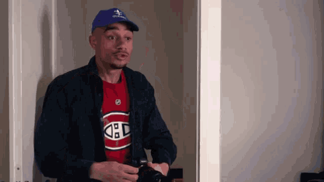 a man wearing a blue hat and a red t-shirt with the letters c and d on it