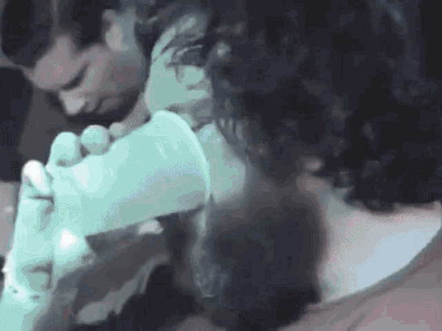 a man with curly hair is using an inhaler on another man 's neck