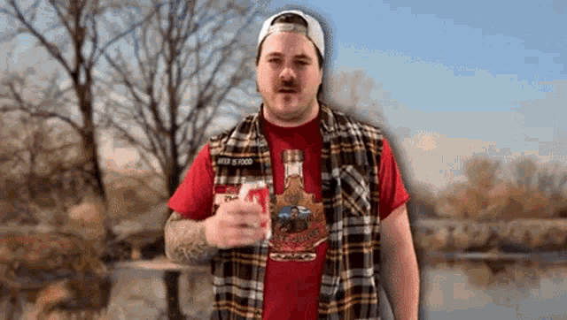 a man wearing a plaid vest and a red shirt holds a glass of beer