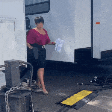 a woman standing next to a trailer holding a piece of paper