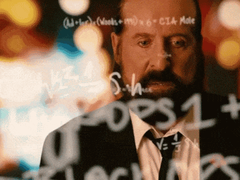 a man in a suit and tie stands in front of a chalkboard with math equations on it